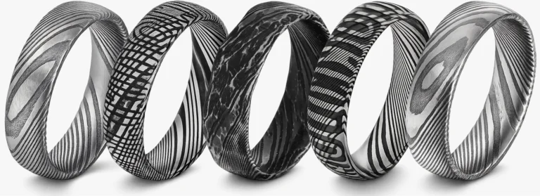 Five Damascus steel rings displayed side by side, each showing a different pattern