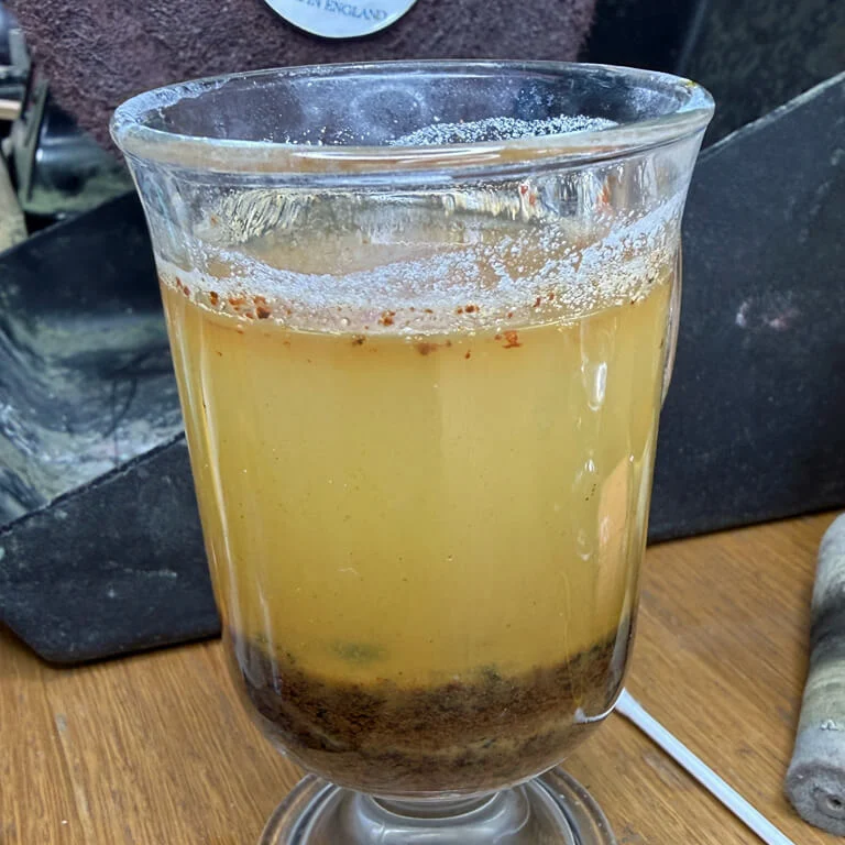 Brown residue settled beneath yellow solution after neutralisation.