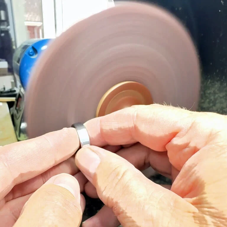 Meteorite and tantalum ring being refinished with a Scotch-Brite wheel before etching.