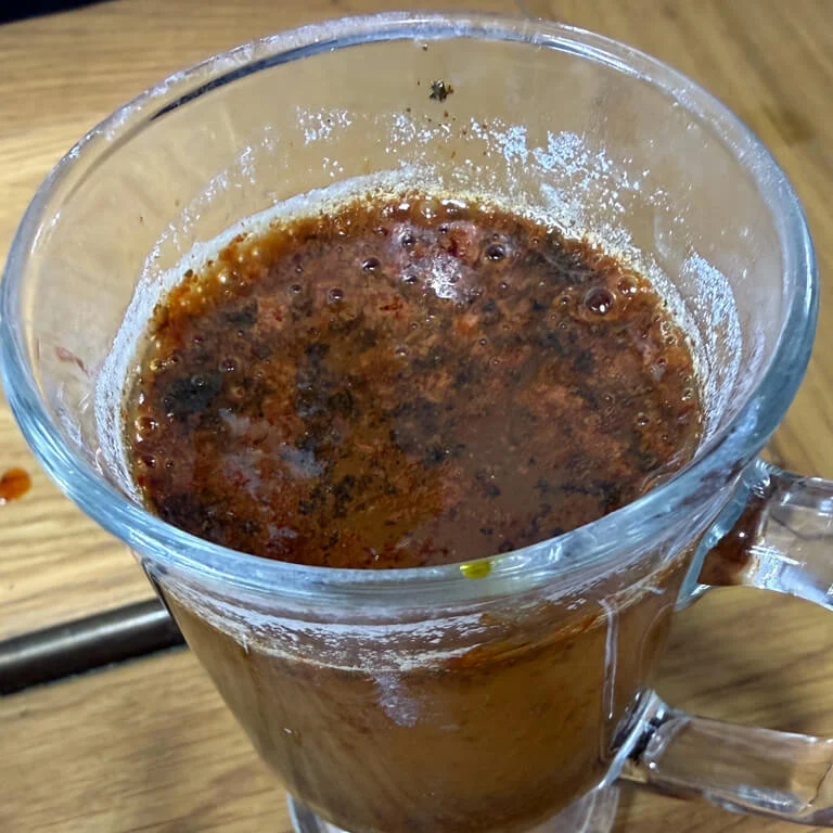 Brown residue suspended in soda crystal solution after meteorite etching.