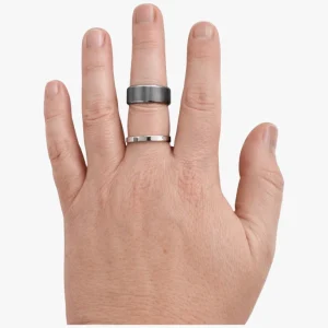 Hand showing two rings, a tantalum and a titanium, showing how different widths fit